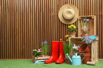 Composition with different gardening tools on artificial grass at wooden wall. Space for text