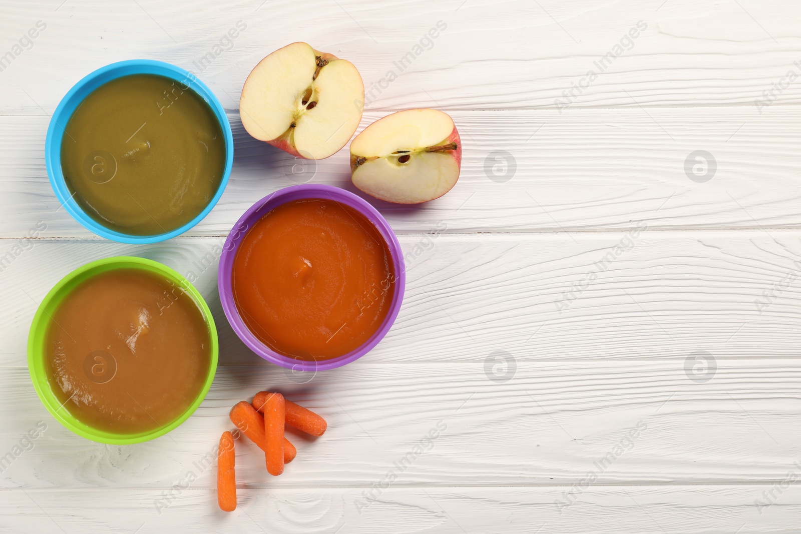 Photo of Baby food. Different purees in bowls and fresh ingredients on white wooden table, flat lay. Space for text