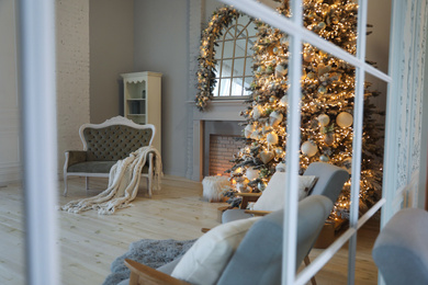 Festive room interior with stylish furniture and beautiful Christmas tree, view through window