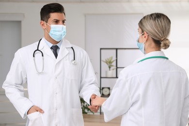 Photo of Doctors with protective masks giving handshake in clinic