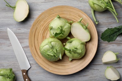 Photo of Whole and cut kohlrabi plants on wooden table, flat lay