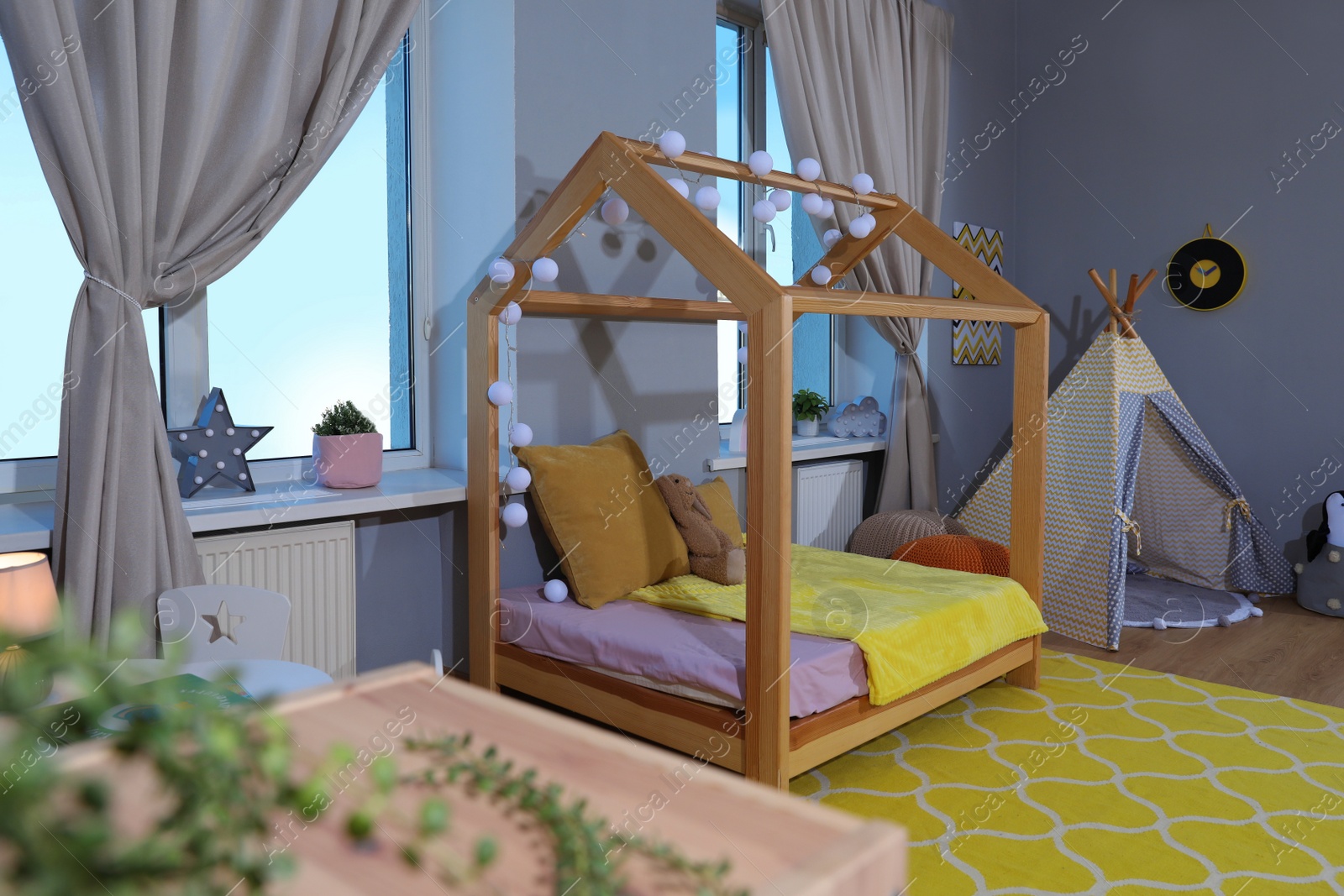 Photo of Stylish child room interior with comfortable house bed and play tent