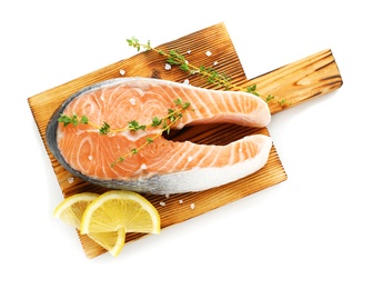 Photo of Wooden board with fresh salmon steak and lemon on white background, top view