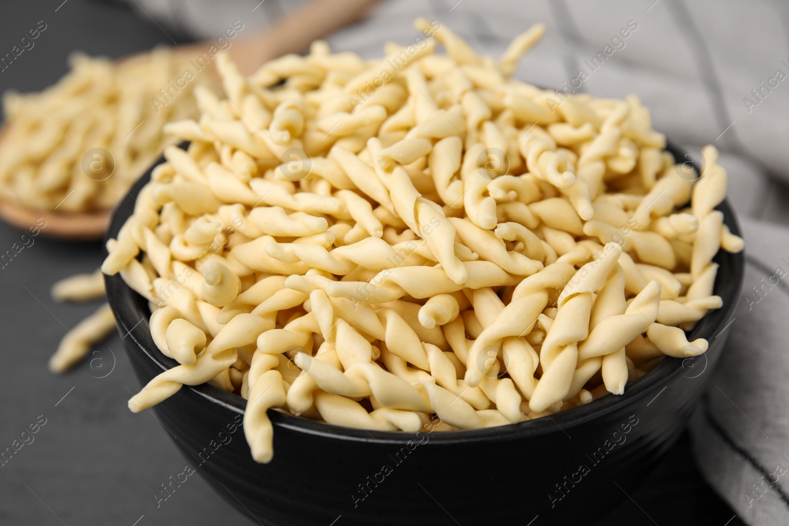 Uncooked trofie pasta in bowl on grey table, closeup Photo of Uncooked trofie pasta in bowl on grey table, closeup