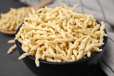 Photo of Uncooked trofie pasta in bowl on grey table, closeup