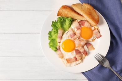 Photo of Fried eggs with bacon and toasted bread on plate served for breakfast, top view