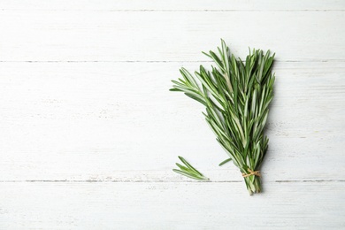 Photo of Bunch of fresh rosemary on white wooden table, top view with space for text