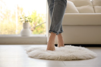 Photo of Woman standing on faux fur rug in living room, closeup. Space for text