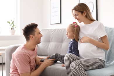 Photo of Young pregnant woman with her family at home