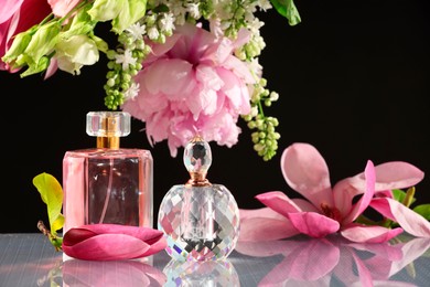 Photo of Luxury perfumes and floral decor on mirror surface against black background