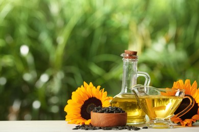 Photo of Sunflower cooking oil, seeds and yellow flowers on white wooden table outdoors, space for text