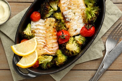 Photo of Tasty cod cooked with vegetables served on wooden table, flat lay
