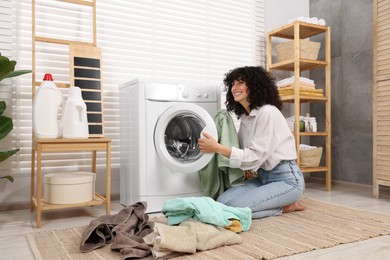 Photo of Woman putting laundry into washing machine indoors