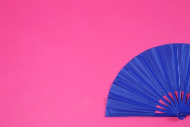 Photo of Blue hand fan on pink background, top view. Space for text