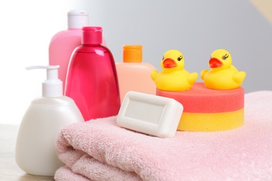 Photo of Baby cosmetic products, toys and towel against color background, closeup