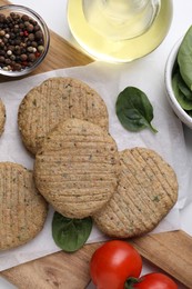 Photo of Raw vegan cutlets and different products on white table, flat lay