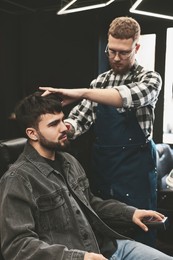 Image of Professional hairdresser working with bearded client in barbershop