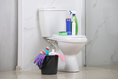 Photo of Cleaning supplies and toilet bowl in bathroom