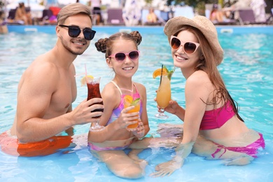 Photo of Happy family with cocktails in pool on sunny day