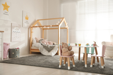 Photo of Small table and chairs with bunny ears in children's bedroom interior