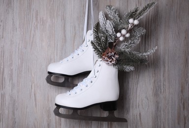 Pair of ice skates with Christmas decor hanging on wooden wall