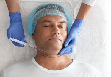 Photo of Mature man with double chin receiving injection in clinic, above view
