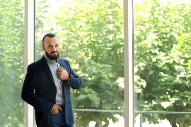 Photo of Portrait of handsome mature man in elegant suit near window. Space for text