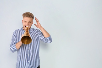 Photo of Young man with megaphone on light background. Space for text