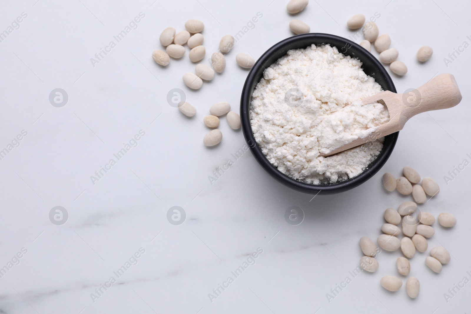 Photo of Bean flour and seeds on white marble table, flat lay. Space for text