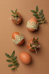 Photo of Festively decorated chicken eggs on brown background, flat lay. Happy Easter