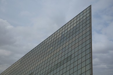 Photo of Low angle view of modern building with many windows against cloudy sky