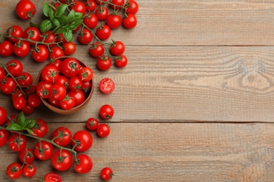 Photo of Fresh cherry tomatoes and basil leaves on wooden table, flat lay. Space for text