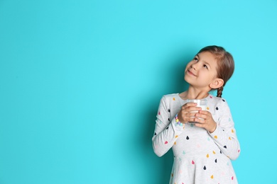 Photo of Cute little girl with glass of milk on color background