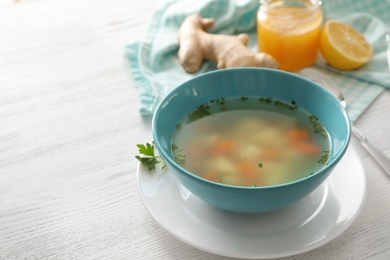 Photo of Bowl of fresh homemade soup to cure flu on wooden table