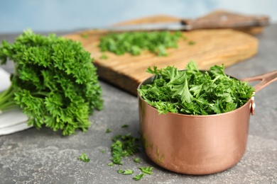 Photo of Composition with saucepan of chopped parsley on grey table, space for text