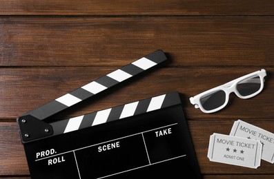 Photo of Clapperboard, movie tickets and 3D glasses on wooden table, flat lay