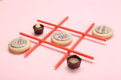 Photo of Tic tac toe game made with cookies and sweets on pink background