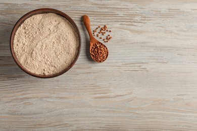 Photo of Bowl with buckwheat flour and seeds on light wooden table, flat lay. Space for text