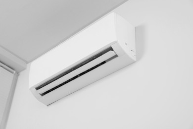 Photo of Modern air conditioner on white wall indoors, low angle view