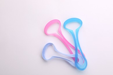 Photo of Three tongue cleaners on white background, top view