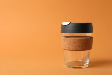 Photo of Glass cup with sleeve on orange background, space for text. Conscious consumption
