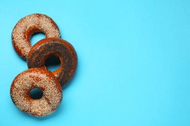 Photo of Many delicious fresh bagels on light blue background, flat lay. Space for text
