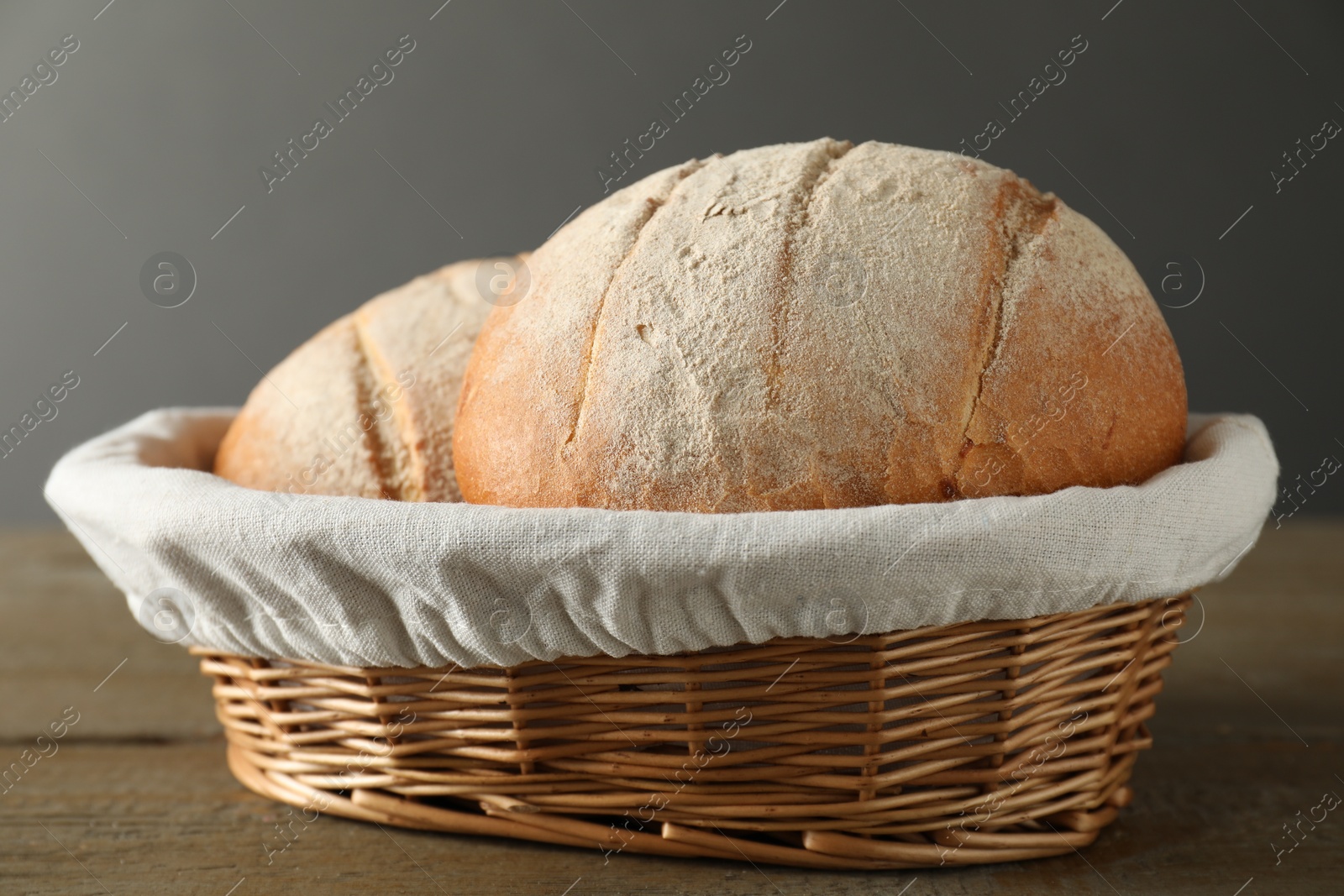 Photo of Wicker basket with fresh bread on wooden table, closeup