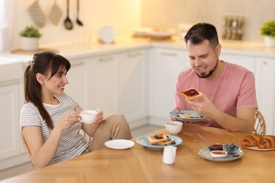 Photo of Happy couple having tasty breakfast at home