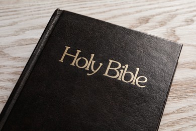 Photo of Bible with dark cover on wooden table, closeup. Christian religious book