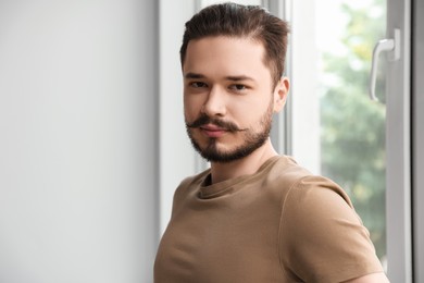 Photo of Handsome man standing near window indoors. Space for text