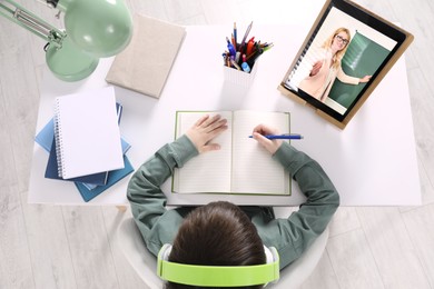 Image of Cute little boy with modern tablet at online lesson, top view. E-learning