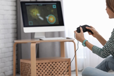 Photo of Young woman playing video game at home