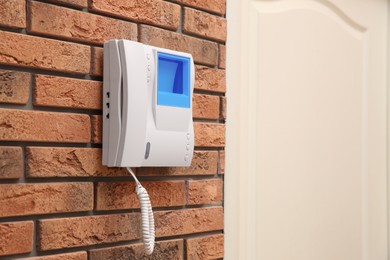 Photo of Modern intercom system with handset on red brick wall indoors, space for text