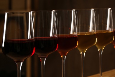 Photo of Glasses of different wines against blurred background, closeup. Expensive collection